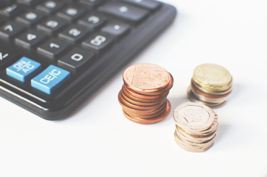 Calculator next to stacks of coins representing fee calculations