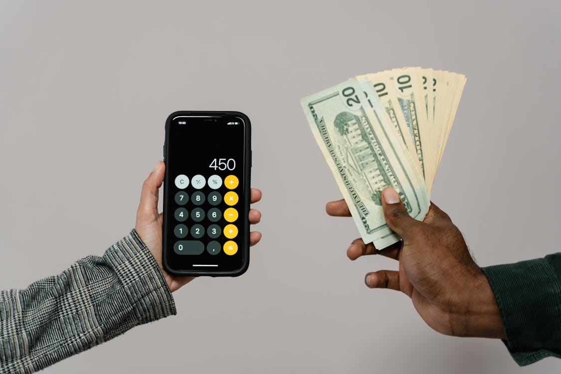 Hands holding a phone calculator and dollar bills representing developer income