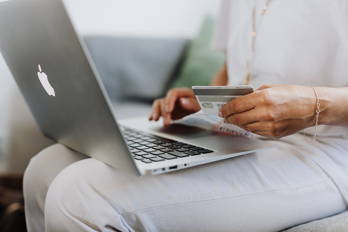 Person making an online purchase on a MacBook with a credit card